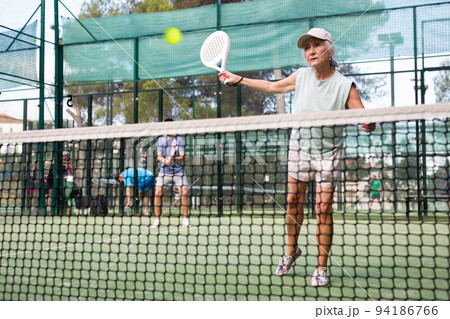 Active elderly woman playing padel tennis on open court 94186766
