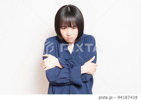 白バックの前で、寒さに震える若い女性 94187438