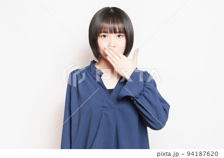 口を手で隠して内緒のポーズをする若い女性 口を手で隠して内緒のポーズをする若い女性 94187620