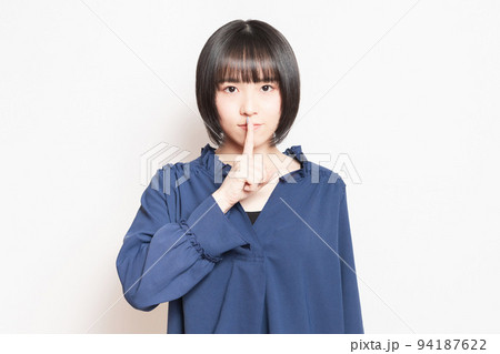 口を手で隠して内緒のポーズをする若い女性 94187622