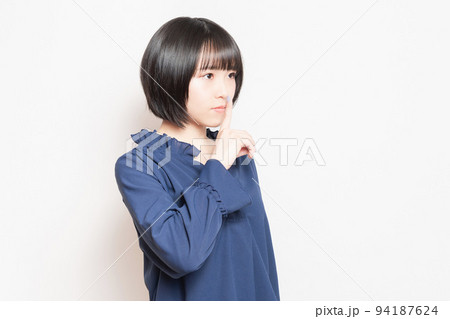 口を手で隠して内緒のポーズをする若い女性 口を手で隠して内緒のポーズをする若い女性 94187624