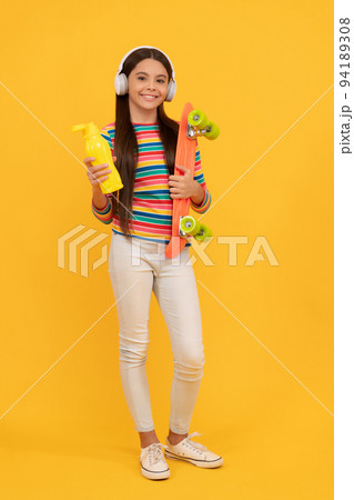 skateboarding. happy child in headphones with penny board. teen girl listen music. skateboarding. happy child in headphones with penny board. teen girl listen music. 94189308