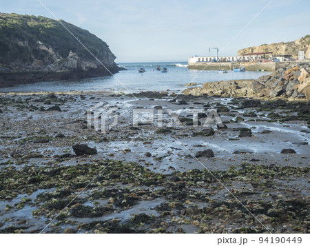 Rocky sea shore at wild Vicentina coast in Porto Covo with groups of fishermans boats anchored in a calm bay Rocky sea shore at wild Vicentina coast in Porto Covo with groups of fishermans boats anchored in a calm bay 94190449