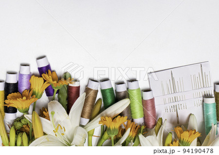 Multicolored threads and flowers on a white background with copy space for text. Greeting card for a seamstress, tailor, needlewoman and atelier for the holidays. Multicolored threads and flowers on a white background with copy space for text. Greeting card for a seamstress, tailor, needlewoman and atelier for the holidays. 94190478
