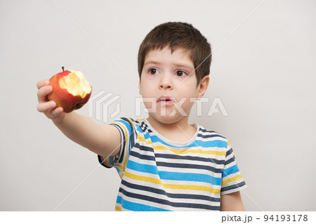 A 4 year old boy eats a red apple and squirms. The child does not like fruit A 4 year old boy eats a red apple and squirms. The child does not like fruit 94193178