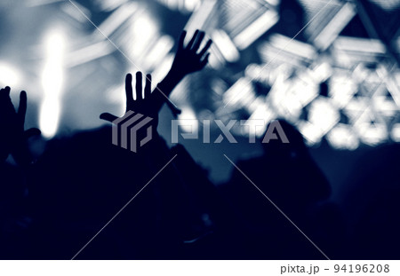 Crowd at a music concert, audience raising hands up, toned 94196208