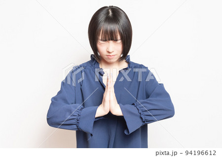 白バックの前で、謝っている若い女性 94196612