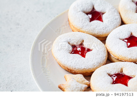 Christmas strawberry linzer cookies on gray background. Festive dessert, winter treat. Christmas strawberry linzer cookies on gray background. Festive dessert, winter treat. 94197513