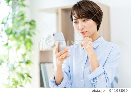 リビングでスマホを操作するミドル女性 94198869