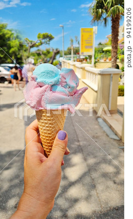 Gelato ice cream cone held up to the hot summer city 94199206