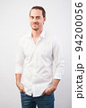 Portrait of young successful young man in white shirt, smiling holding hands in pockets over gray wall. Confidence and business concept. Portrait of young successful young man in white shirt, smiling holding hands in pockets over gray wall. Confidence and business concept. 94200056