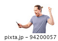 Concept of winning a lottery or a sweepstake. Man rejoices looking at his smartphone. Concept of winning a lottery or a sweepstake. Man rejoices looking at his smartphone. 94200057