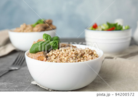 Tasty buckwheat porridge with meat on grey table 94200572