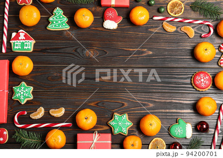 Frame made with tasty Christmas cookies and tangerines on wooden background, flat lay Frame made with tasty Christmas cookies and tangerines on wooden background, flat lay 94200701