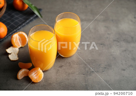 Fresh tangerines and glasses of juice on grey table. Space for text Fresh tangerines and glasses of juice on grey table. Space for text 94200710