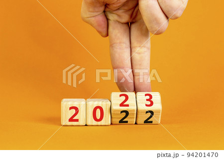 2023 happy new year symbol. Businessman turns cubes, symbolize the change from 2022 to the new year 2023. Beautiful orange table orange background. Copy space. Business 2023 happy new year concept. 2023 happy new year symbol. Businessman turns cubes, symbolize the change from 2022 to the new year 2023. Beautiful orange table orange background. Copy space. Business 2023 happy new year concept. 94201470