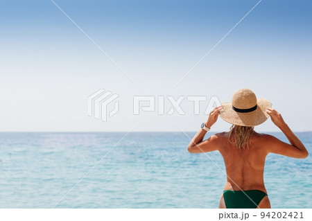 Beautiful blond woman in a straw hat on the beach of Corfu Beautiful blond woman in a straw hat on the beach of Corfu 94202421