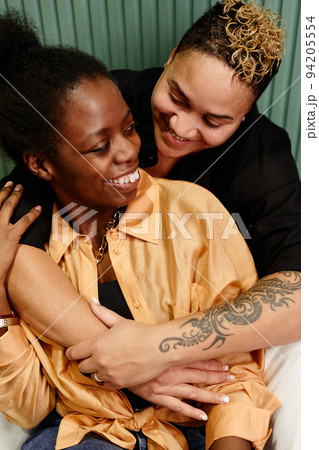 Happy young lesbian woman with tattoo on arm giving hug to her girlfriend Happy young lesbian woman with tattoo on arm giving hug to her girlfriend 94205554