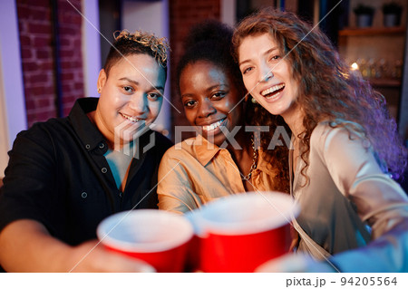 Cheerful pretty girls clinking with plastic glasses and looking at camera 94205564