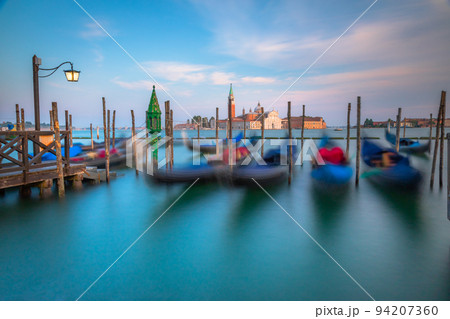 Gondole docked by wooden mooring poles in grand canal, Ethereal Venice, Italy Gondole docked by wooden mooring poles in grand canal, Ethereal Venice, Italy 94207360