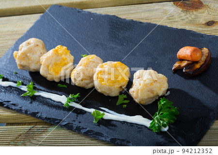 Dish of dumplings with tasty white fish served with greens at plate 94212352