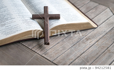 Wooden cross on top of an open bible Wooden cross on top of an open bible 94212581