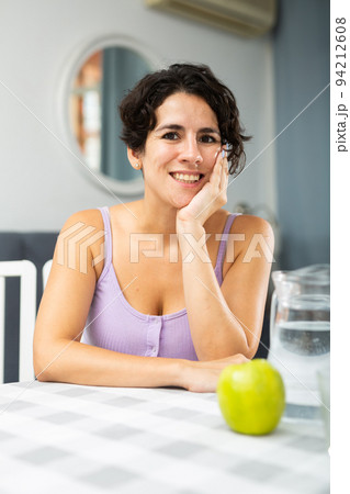Portrait of woman sitting at a table in her apartment room 94212608