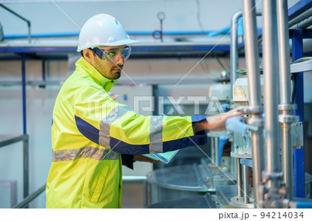 Senior professional quality control officer inspecting the manufacturing line and computer system in the beverage bottling factory. Industrial or machinery engineer inspecting and fixing the machines. Senior professional quality control officer inspecting the manufacturing line and computer system in the beverage bottling factory. Industrial or machinery engineer inspecting and fixing the machines. 94214034