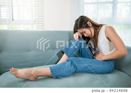 Asian young woman unhappy hands holding on stomach suffering from abdominal pain Asian young woman unhappy hands holding on stomach suffering from abdominal pain 94214696