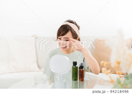 家で笑顔で鏡を見る女性（コンタクトレンズ・眉毛） 94218496