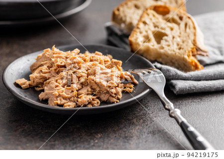 Canned tuna fish on the plate on black table. Canned tuna fish on the plate on black table. 94219175