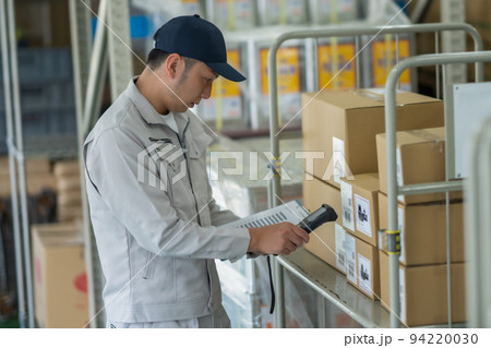 バーコードラベルをスキャンする倉庫の男性スタッフ 94220030