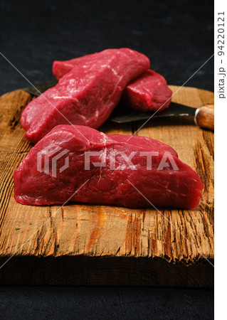 Closeup view of raw beef steak chopped on slices on cutting board 94220121