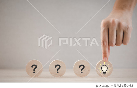 closeup hand holding round wood piece with light bulb icon 94220642