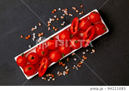Fresh washed cherry tomatoes and paprika slices on a white oblong dish with pink salt and water drops on a black Fresh washed cherry tomatoes and paprika slices on a white oblong dish with pink salt and water drops on a black 94221083