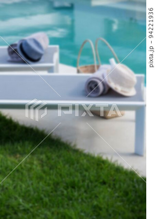 Hats and towels on tables at poolside 94221936
