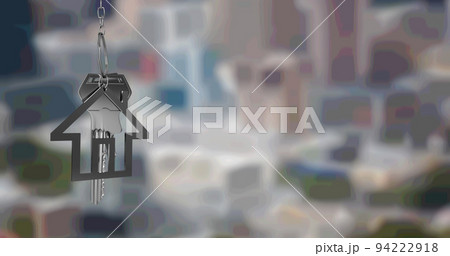 Image of silver house key fob and key, hanging in front of blurred cityscape 94222918
