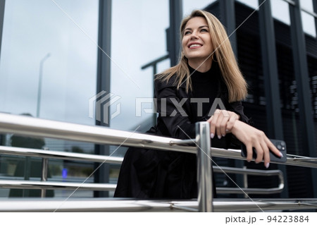 Business successful middle-aged blonde woman with a smile looks into the distance against the 94223884