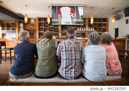 Group of senior people watching football match siting together in bar Group of senior people watching football match siting together in bar 94226200