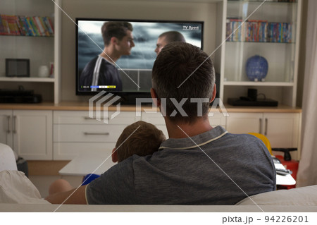 Father and son watching football match siting together on the couch 94226201