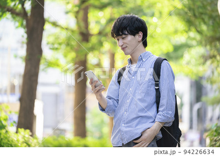 スマートフォンを持った笑顔の若い男性 スマートフォンを持った笑顔の若い男性 94226634