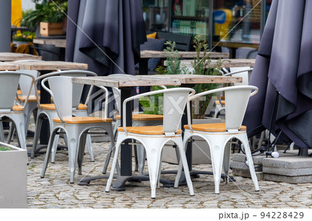 Empty table in outdoor cafe or restaurant. Tables and chairs at sidewalk cafe. Touristic setting, cafe table, sidewalk cafe furniture. Empty table in outdoor cafe or restaurant. Tables and chairs at sidewalk cafe. Touristic setting, cafe table, sidewalk cafe furniture. 94228429