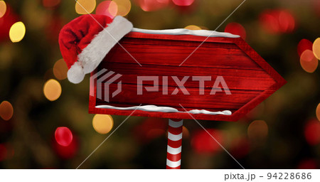 Image of christmas arrow with santa hat over blurred lights 94228686