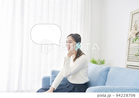 リビングで笑顔でスマホで電話する女性　吹き出しあり 94228706