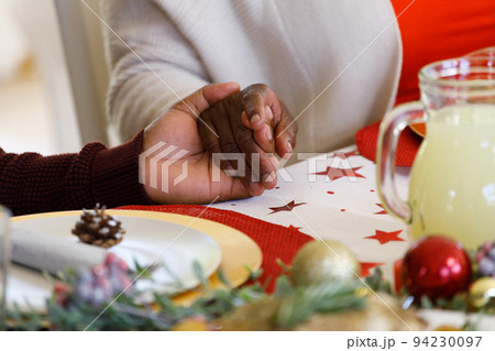 Multi generation african american family sitting at table and praying before dinner Multi generation african american family sitting at table and praying before dinner 94230097