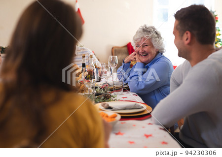 Caucasian family sitting at table for christmas dinner together and smiling 94230306