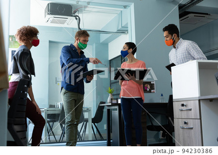 Diverse group of work colleagues wearing masks in discussion office Diverse group of work colleagues wearing masks in discussion office 94230386