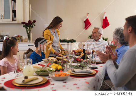Multi generation caucasian family sitting at table for dinner together 94230448