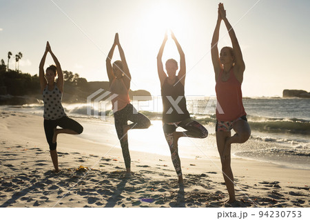 Women doing yoga on the beach 94230753