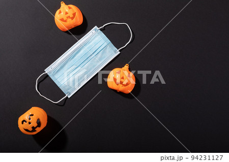 Three halloween pumpkin toys and face mask against grey background 94231127
